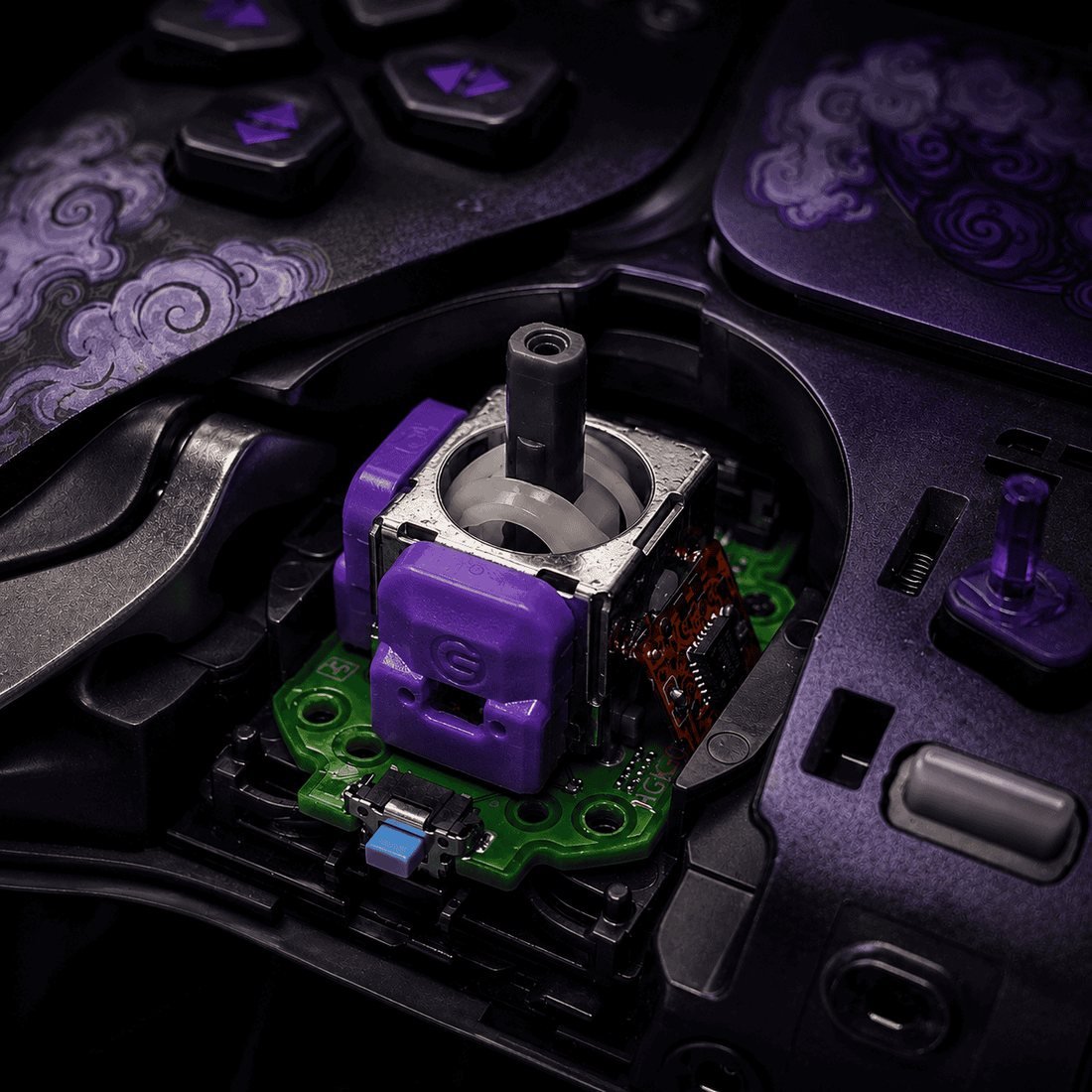 A purple Hall Effect thumbstick module seated on the circuit board inside an opened GameCosmos controller, with the patterned faceplate lifted away